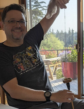 The author using a drop spindle to make yarn.